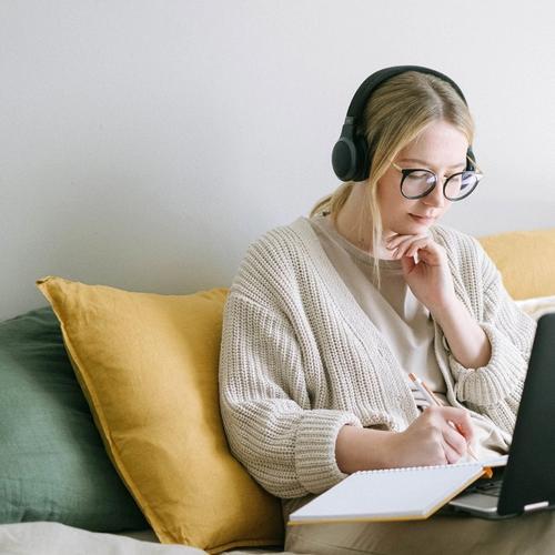 Woman writing with computer and notepad