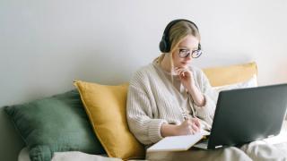 Woman writing with computer and notepad